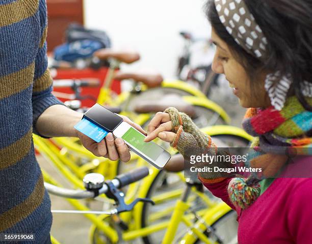 Woman using mobile payment device in bike shop.