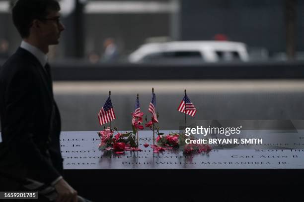 Man walks past American flags and flowers lining the memorial pool at the National September 11 Memorial to mark the 22nd anniversary of the 9/11...