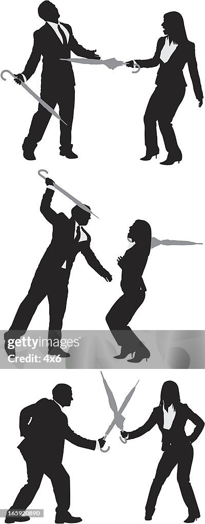 Business couples fighting with umbrellas