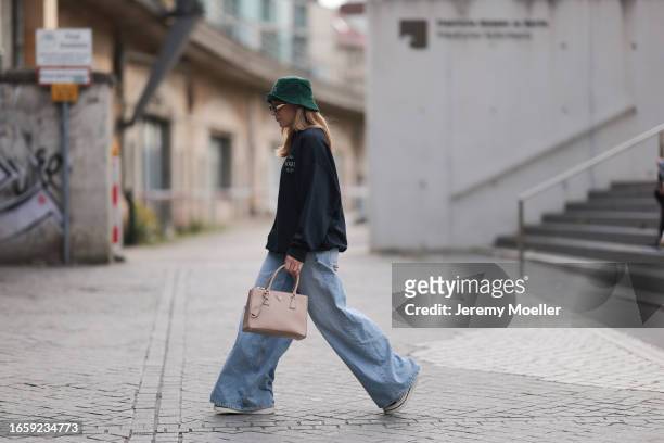 Sonia Lyson seen wearing Celine gold metal Triomphe sunglasses, Vogue Collection green logo bucket hat, Vogue Collection dark blue oversized sweater,...