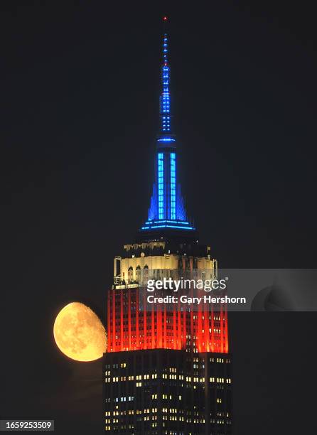 Percent waning gibbous moon rises behind the Empire State Building lit in red, white, and blue to mark Labor Day weekend in New York City on...