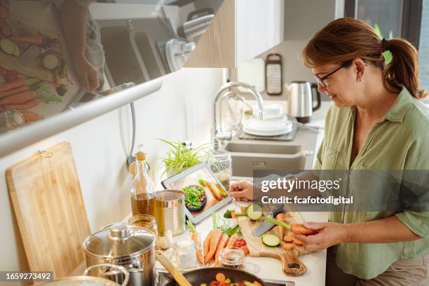 woman looking for healthy ingredients on digital tablet - housewife stock pictures, royalty-free photos & images