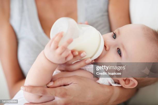 baby girl drinking milk from bottle - baby bottle stockfoto's en -beelden