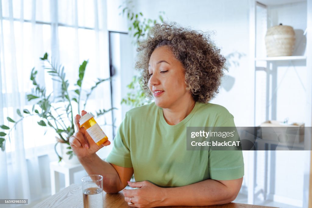 Mature woman holding a bottle of medicine in her hand