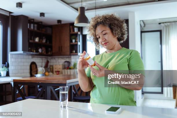 mujer madura sosteniendo un frasco de medicina en la mano - tomar medicina fotografías e imágenes de stock