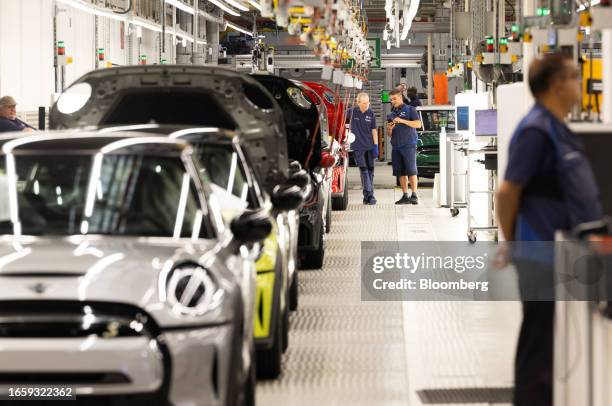 Employees next to Mini Cooper S cars on the production line at BMW AG's Mini final assembly plant in Cowley near Oxford, UK, on Monday, Sept. 11,...