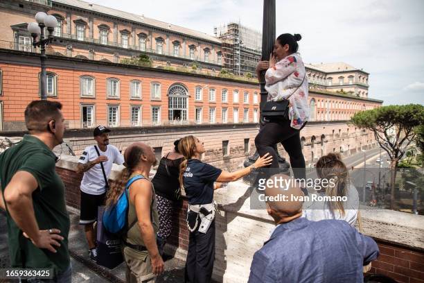 Municipal police officer talks to a woman clinging to a lamppost suspended about 20 meters away during a protest against the decision to abolish the...