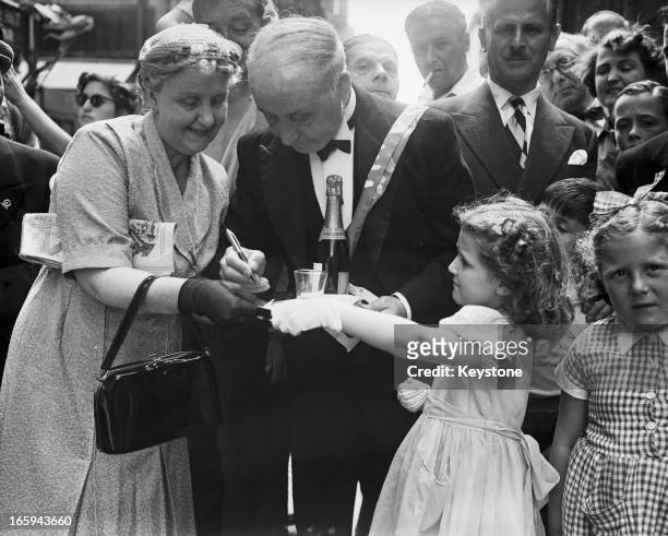 Year-old waiter Salvatore Criscuolo signs an autograph for seven year-old Raewyn Ann Williams of New Zealand after he won a silver cigarette case and...