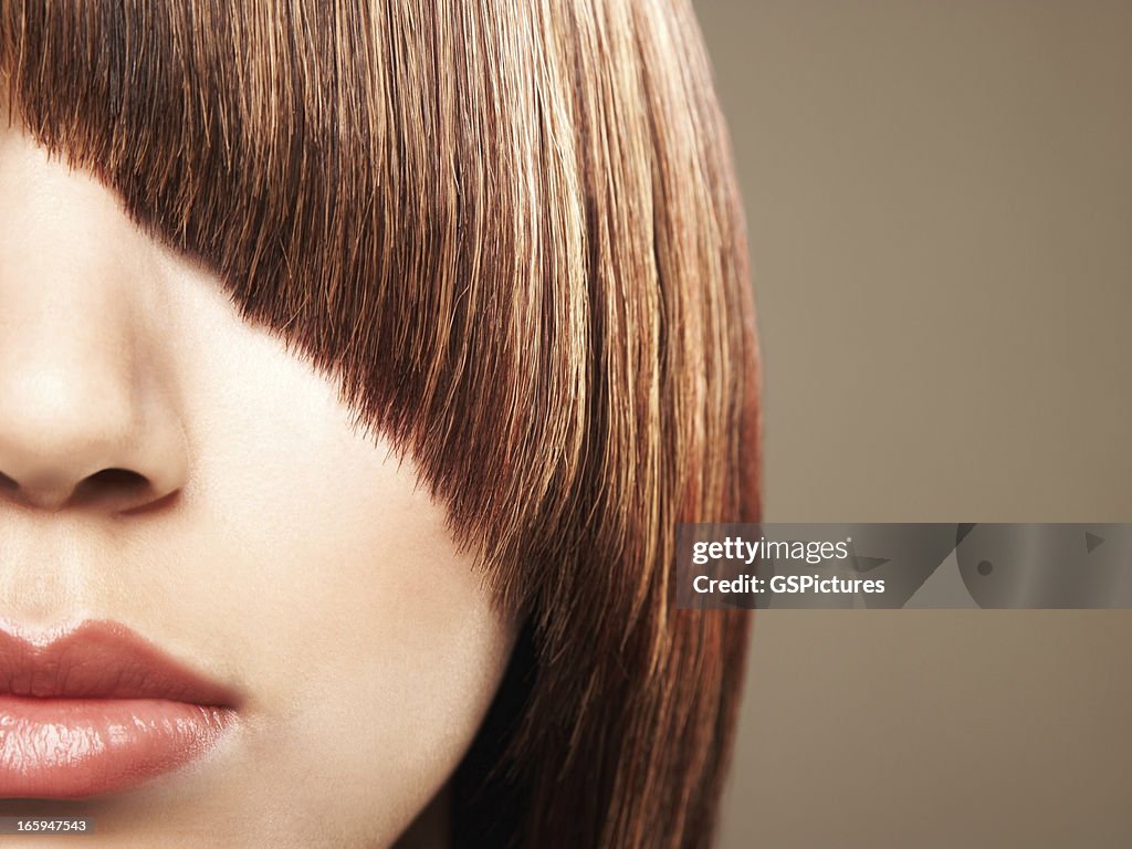 Close up crop of woman's bangs coverin her eye