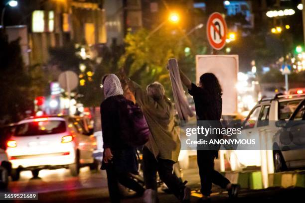 Tehran, Iran. Iranian women remove their mandatory hijabs and flash victory signs amid the ongoing night traffic. The nationwide protests started...