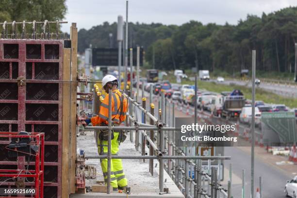 Workman removes concrete shuttering as part of roadworks on the A3 trunk road near to the National Highways project to improve the Wisely interchange...