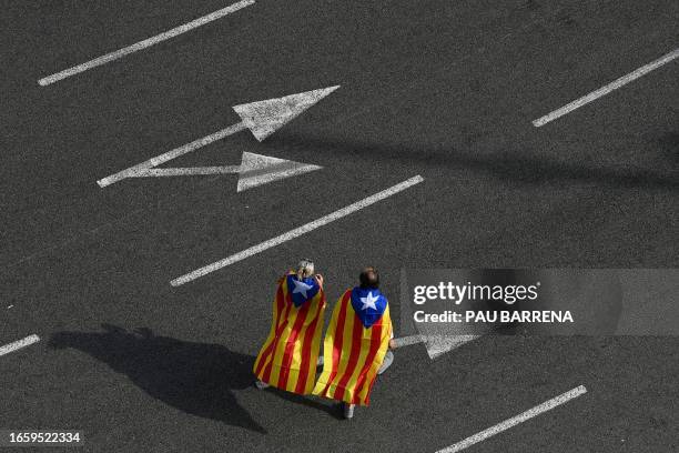 Demonstrators wrapped with Catalan pro-independence "Estelada" flags arrive for the "Diada" celebrations, the national day of Catalonia, on the Plaza...