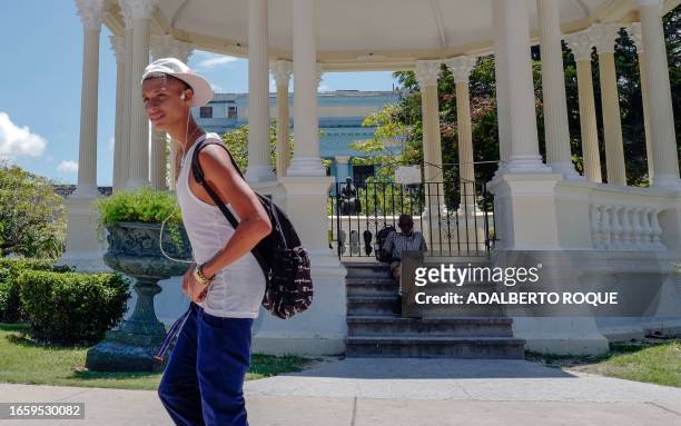 Young man walks past an elderly man in Santa Clara, Villa Clara province, Cuba, on September 11, 2023.
