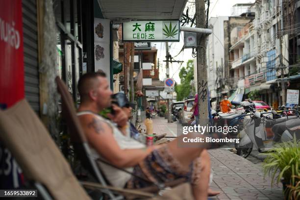 Person smokes a joint in front of a cannabis dispensary along Khao San Road in Bangkok, Thailand, on Sunday, Sept. 10, 2023. An ongoing regulatory...