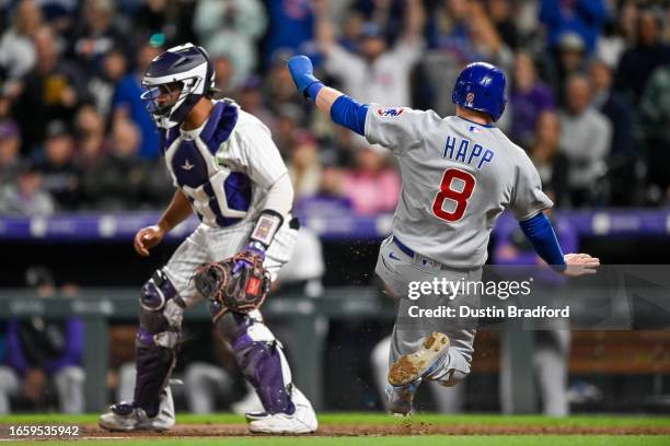 Ian Happ of the Chicago Cubs scores in the ninth inning as Elias Diaz of the Colorado Rockies waits for the throw at Coors Field on September 11,...