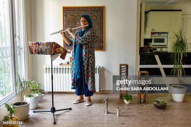 Tehran, Iran. Niloofar Ebrahimi is 42 years old and is a Flute player who is standing and playing in her house.