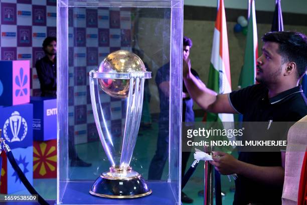Man cleans the housing of the ICC Men's Cricket World Cup 2023 trophy on display at a school as part of an official trophy tour in Mumbai on...