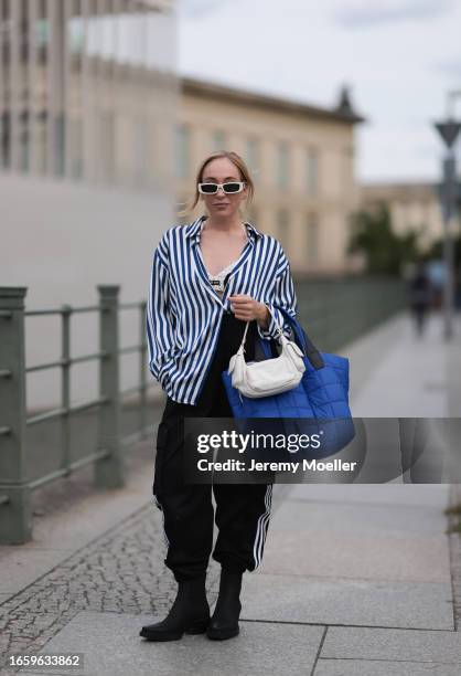 Sonia Lyson seen wearing Linda Farrow white sunglasses, Zara blue / white striped blouse, Adidas black jogger cargo pants, Miu Miu black / white knit...