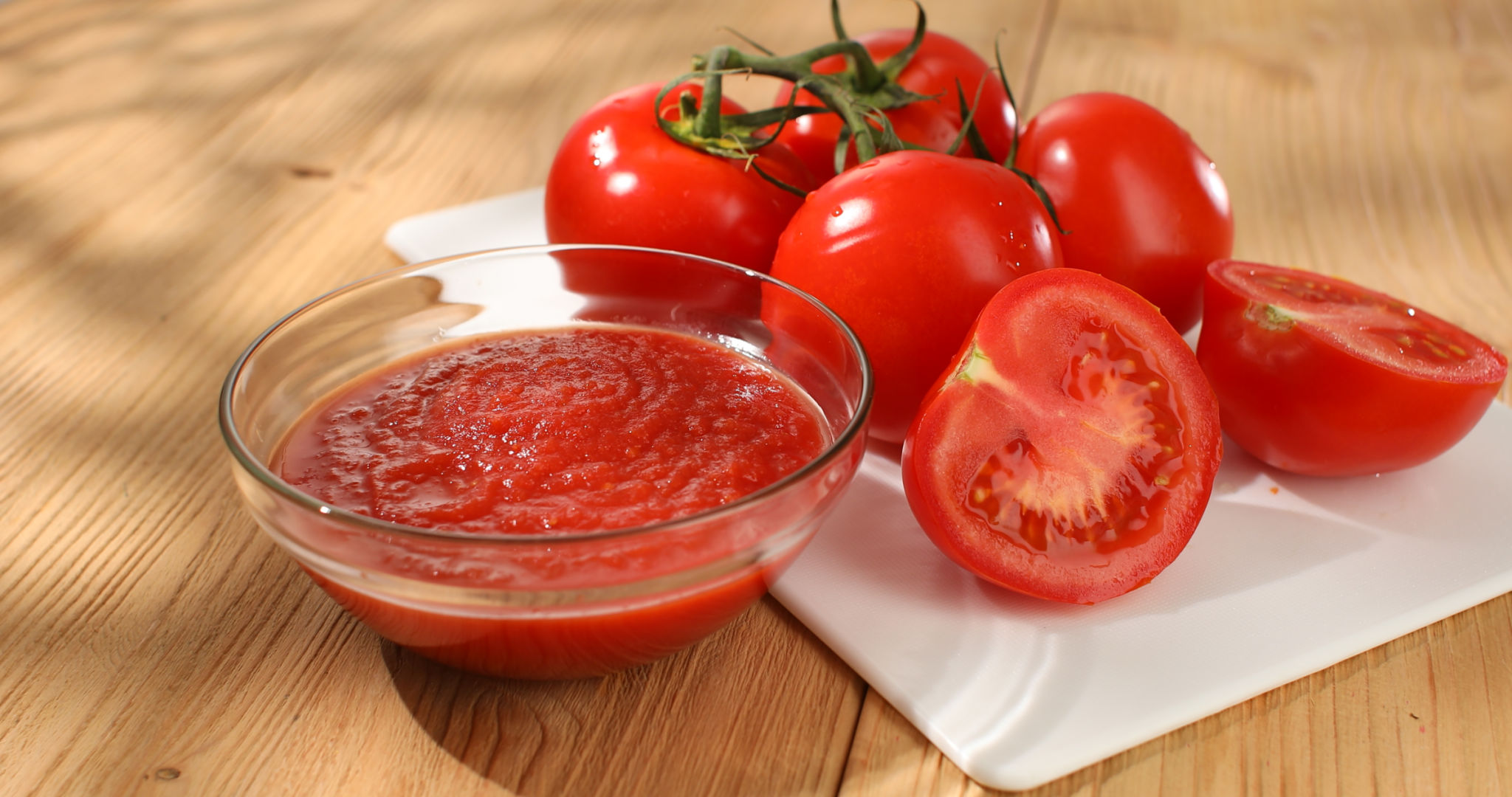Tomato puree in a bowl with tomatoes on a cutting board. Cooking sauce for food. Tomato puree in a bowl with tomatoes on a cutting board. Cooking sauce for food.