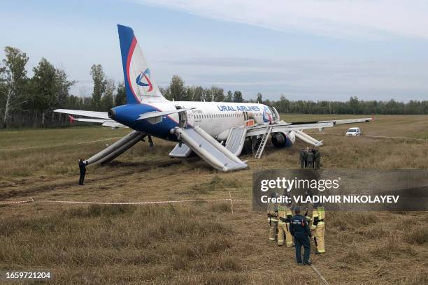 Law enforcement officers stand next to an Ural Airlines Airbus A320 passenger plane following its emergency landing in a field near the village of...