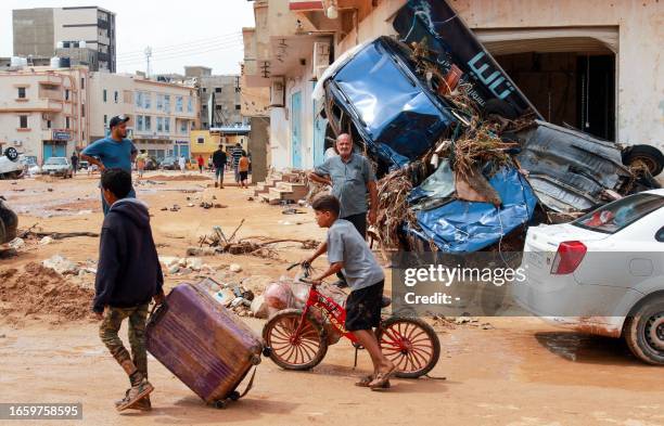 Boy pulls a suitcase past debris in a flash-flood damaged area in Derna, eastern Libya, on September 11, 2023. Flash floods in eastern Libya killed...