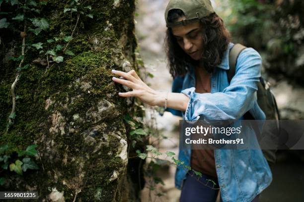 woman hiker holding a big rock walking down forest trail - duurzaam toerisme stockfoto's en -beelden