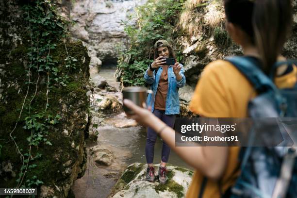 young woman friends taking photos on forest hike - eco tourism stock pictures, royalty-free photos & images