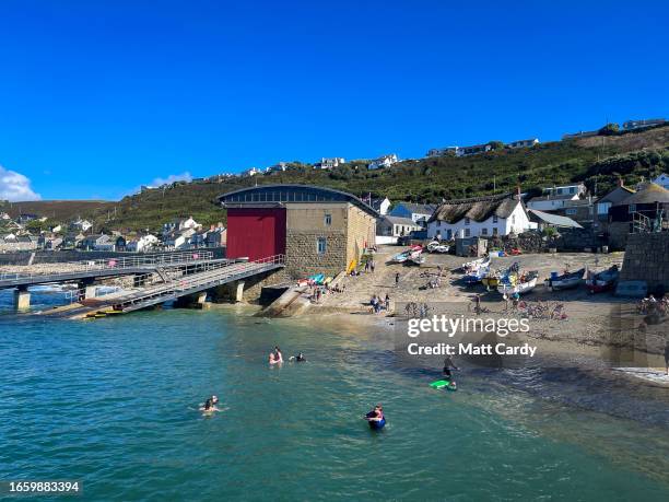 People swim in the sea at the harbour at Sennen Cove on August 14, 2023 in Cornwall, England. The county of Cornwall, in the south west of England,...