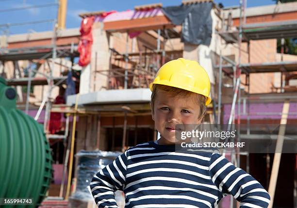 boy wearing hard hat in front of building shell - boy in hard hat photos et images de collection