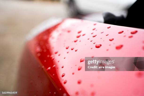 close-up view of red car parked outside the office on a rainy winter day, droplets sliding down the bodywork. - bodywork stock pictures, royalty-free photos & images