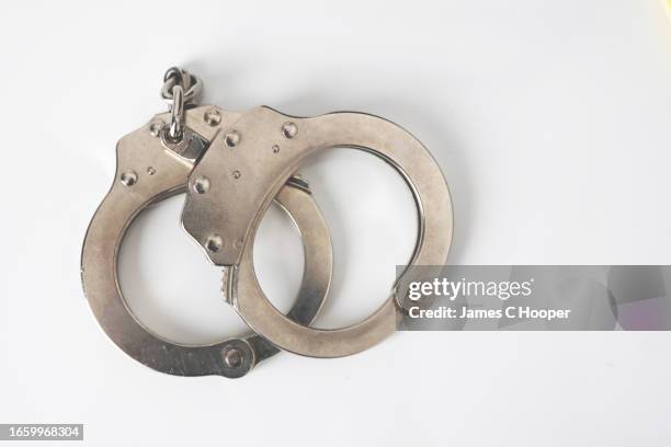 handcuffs on white background 1 - under arrest stock pictures, royalty-free photos & images