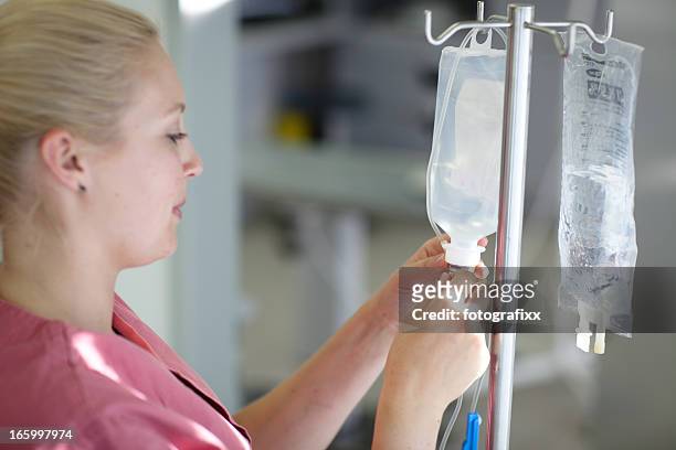 female nurse is preparing an iv drip - infuus stockfoto's en -beelden