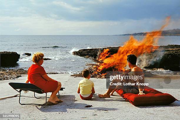family watching campfire burning down 1970 - fire beach stock pictures, royalty-free photos & images