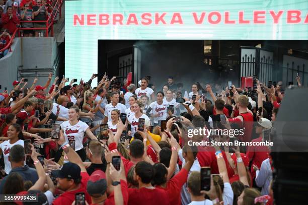 The Nebraska Cornhuskers make their way through fans on the way to the court before the match against the Omaha Mavericks at Memorial Stadium on...