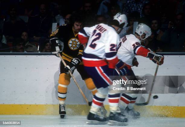 John Wensink of the Boston Bruins battles with Mike Bossy and Bryan Trottier of the New York Islanders on October 15, 1977 at the Nassau Coliseum in...