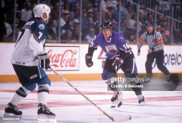 Brett Hull of the Western Conference and St. Louis Blues skates with the puck as he is defended by Paul Coffey of the Eastern Conference and...