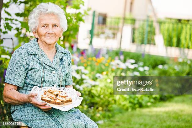 hübsche großmutter holding eine platte mit kuchen - 80 jahre torte stock-fotos und bilder