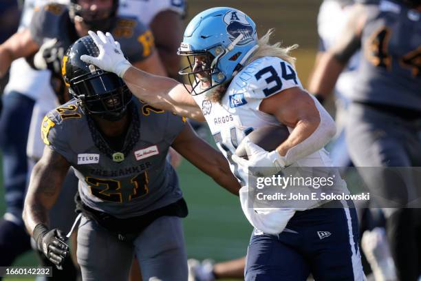 Ouellette of the Toronto Argonauts straight arms Simoni Lawrence of the Hamilton Tiger-Cats to gain yards during the second half at Tim Hortons Field...