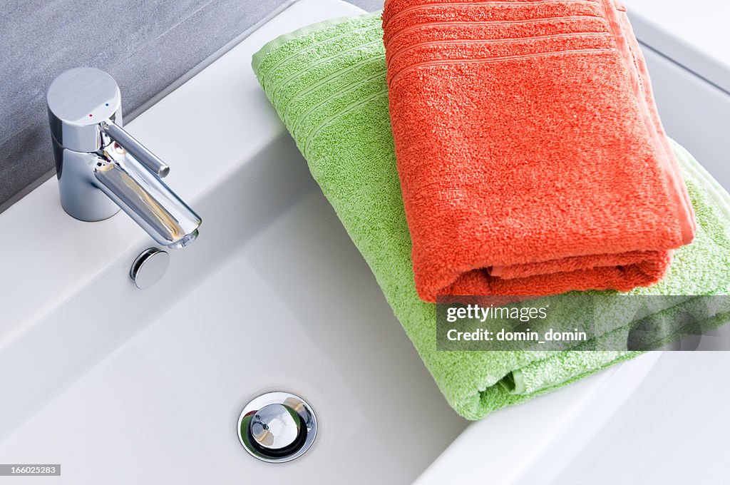 Rectangular bathroom sink with one green and one orange towel