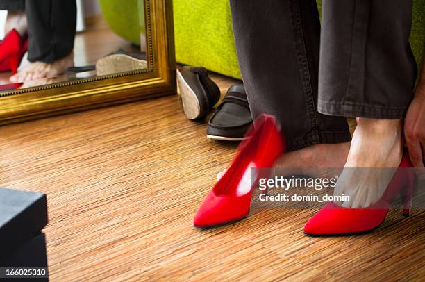 close-up of man trying on red woman's high-heels, wardrobe interior - high heels photos stockfoto's en -beelden