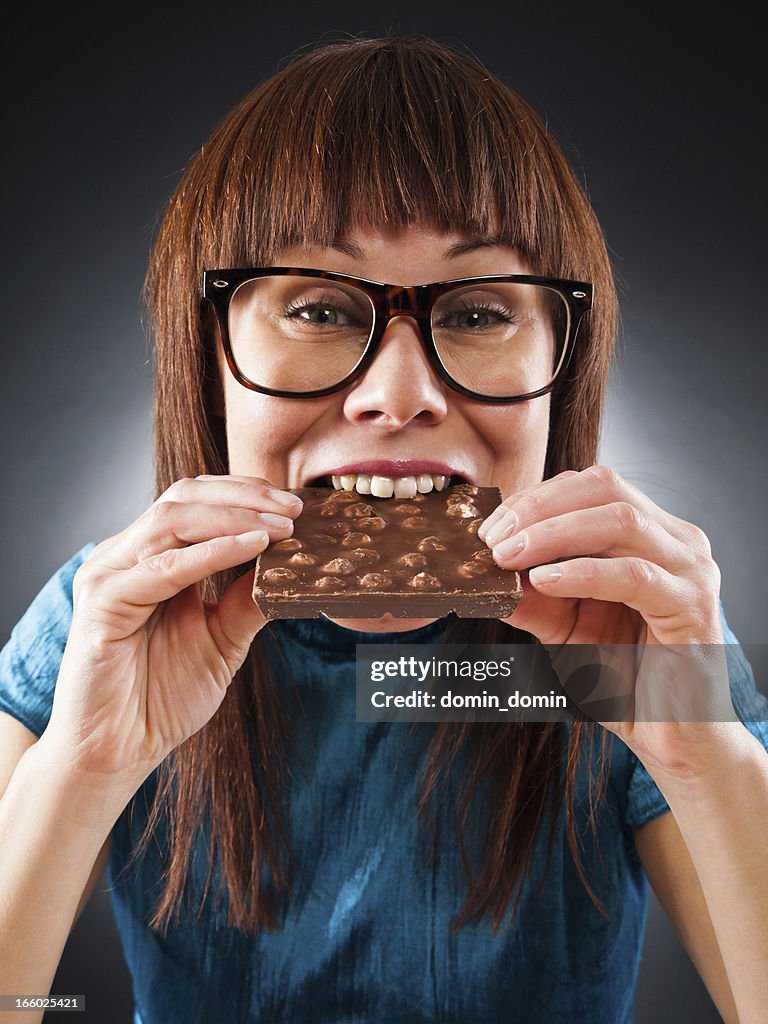Portrait of slim woman eating chocolate with nuts, studio shot