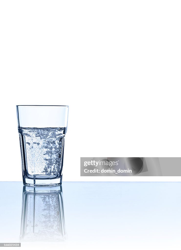 Ein Glas Mineralwasser in Blau, isoliert auf weiss