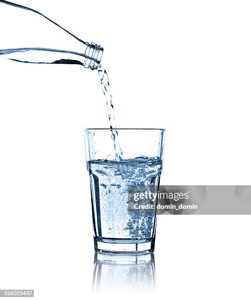 pouring water from bottle into glass, studio shot, isolated - glas bottle stock pictures, royalty-free photos & images