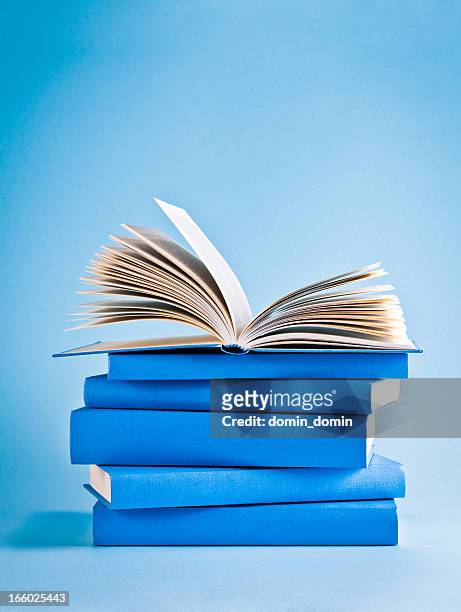 opened book on top of stack of blue books, knowledge - boek stockfoto's en -beelden