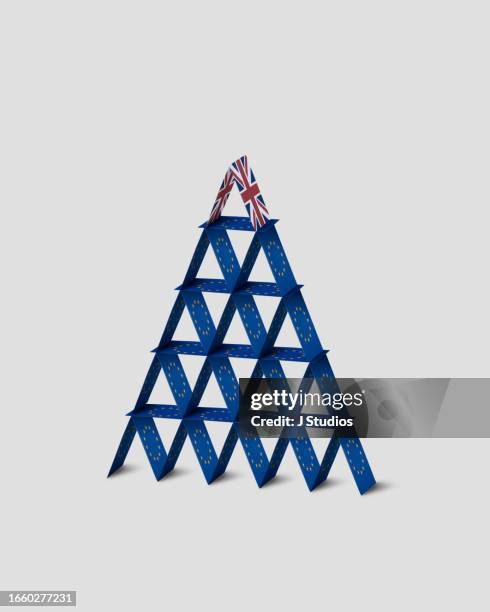 house of cards made out of european flags with a single british flag at the top - brexit uncertainty stock pictures, royalty-free photos & images