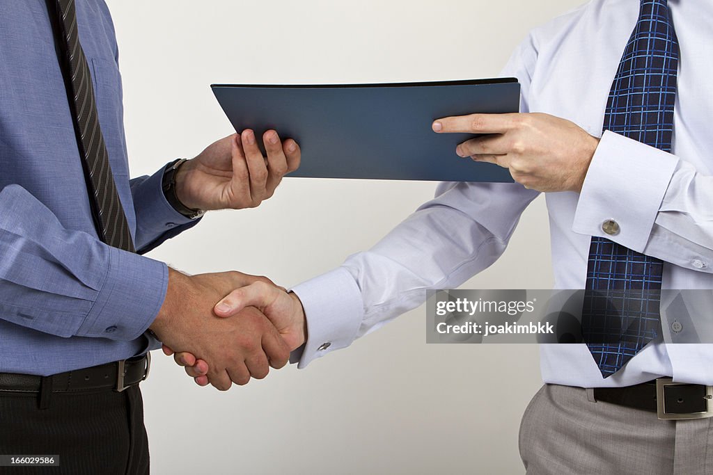 Two businessmen shaking hands with a document