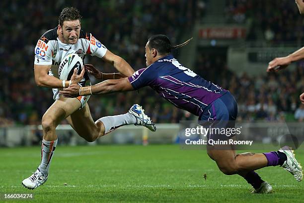 Tim Moltzen of the Tigers is tackled by Mahe Fonua of the Storm runs through the banner during the round 5 NRL match between the Melbourne Storm and...