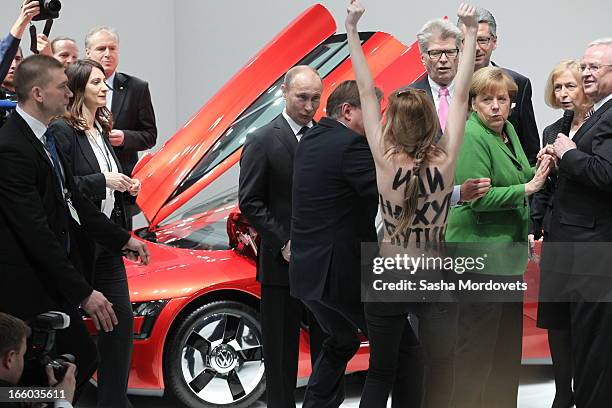 Russian President Vladimir Putin is attacked by an activist of the Ukrainian women rights group 'Femen' as German Chancellor Angela Merkel looks on...