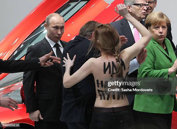 Russian President Vladimir Putin is attacked by an activist of the Ukrainian women rights group 'Femen' as German Chancellor Angela Merkel looks on...