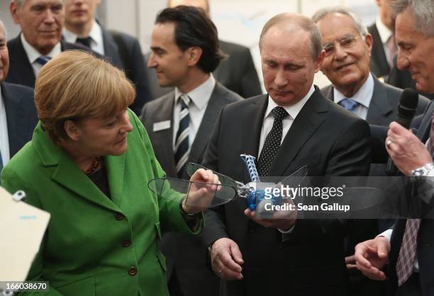 German Chancellor Angela Merkel and Russian President Vladimir Putin look at a remote-controlled drone called a BionicOpter that looks like a...